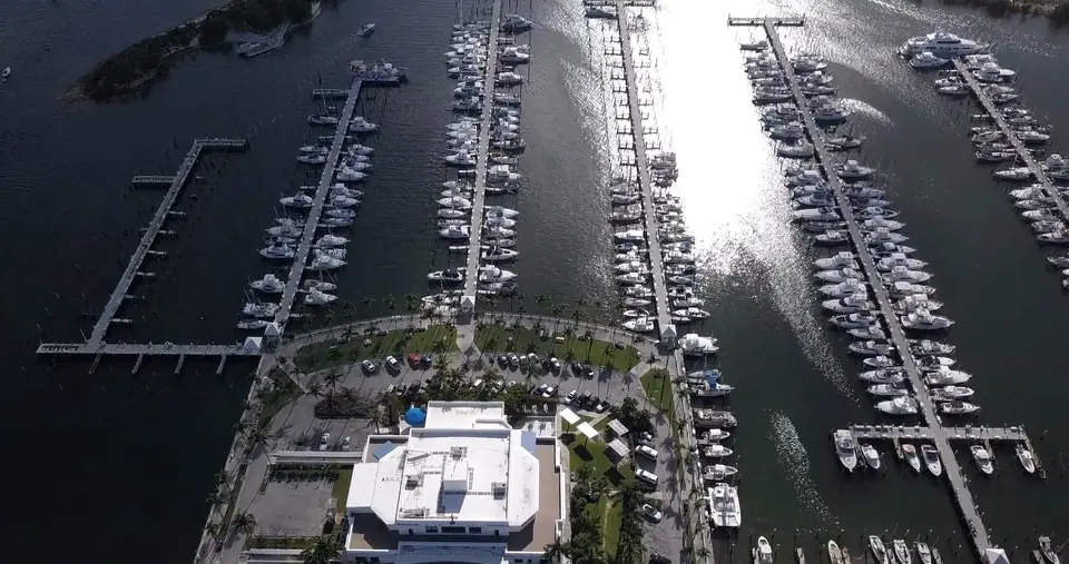 Top-down aerial view of a marina (the stock page tags it Miami): rows of moored boats and sun on the water.