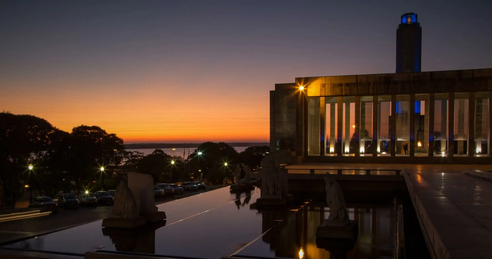 The Monumento a la Bandera, Rosario, at dawn, with its reflecting pool and an orange sky over the Parana.