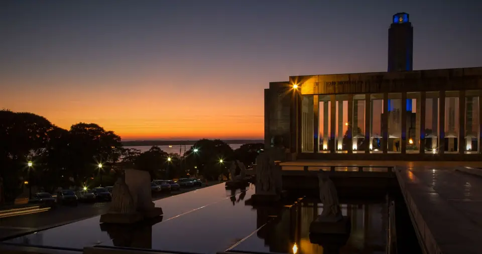 The Monumento a la Bandera, Rosario, at dawn, with its reflecting pool and an orange sky over the Parana.