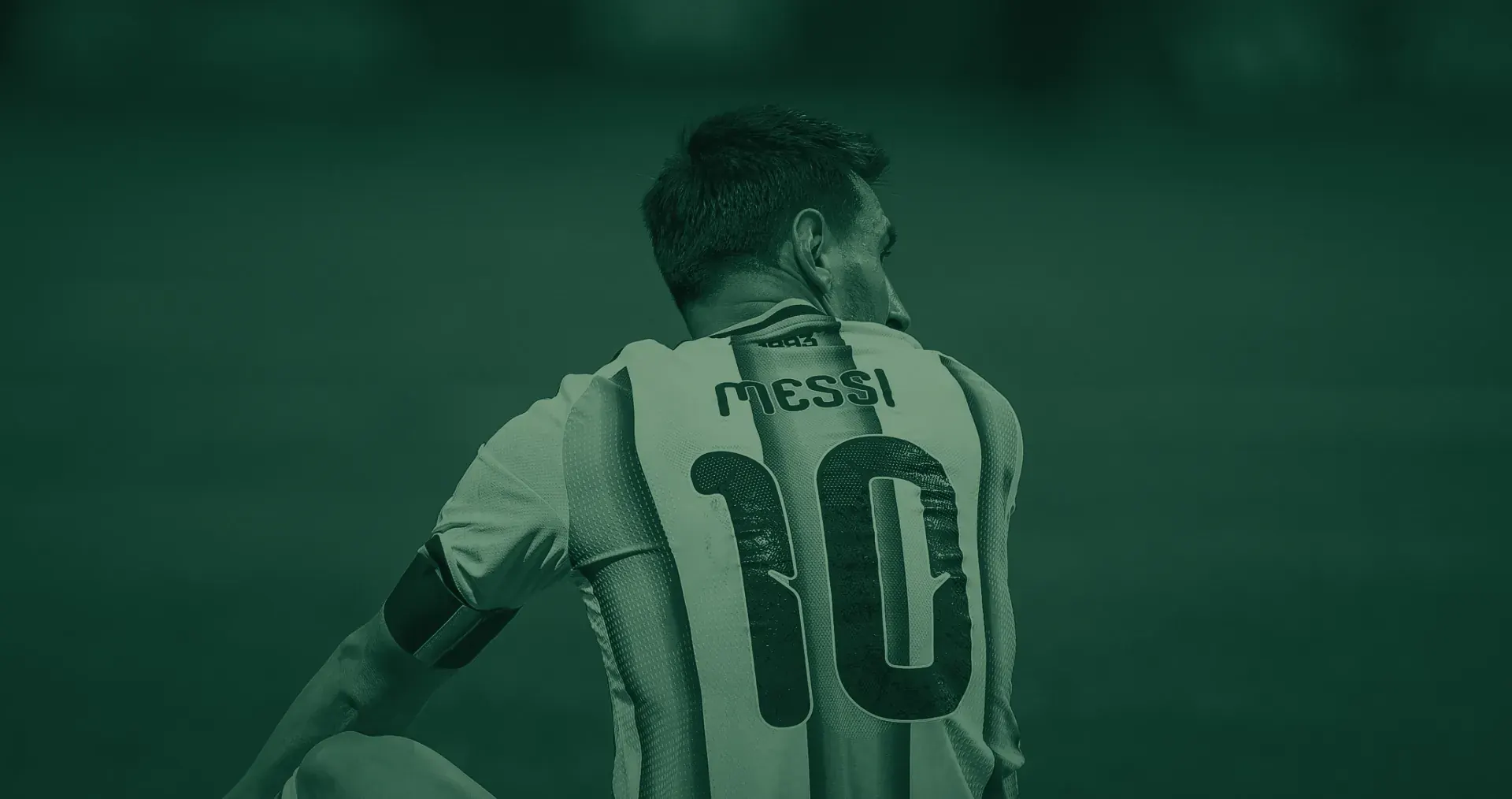 Messi seated on the grass, seen from behind and turning his head, in Argentina's 10 shirt, against plain green. Argentina v Egypt, 7 July 2026.